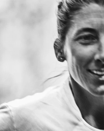 Close-up black and white portrait of a smiling woman wearing a t-shirt photographed by Benjamin Rasmussen.
