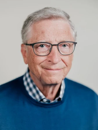 Portrait of Bill Gates wearing dark glasses and blue sweater against a plain white background by Benjamin Rasmussen
