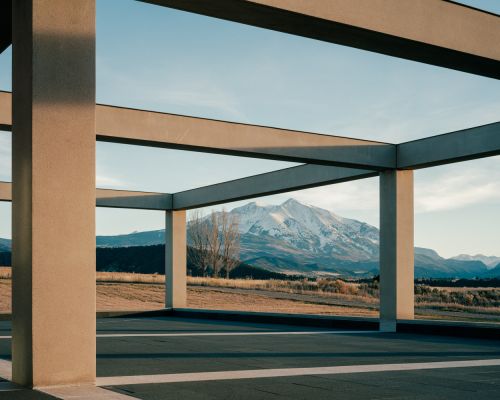 Architectural frame with view of snow-capped mountains under a clear sky, creating a contrast between built structure and natural landscape.