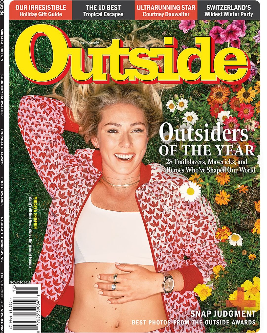 Magazine cover of Outside featuring a smiling adult woman in a patterned jacket lying in a field of grass and flowers.