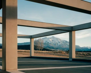 Architectural concrete frame framing a snow-capped mountain peak and open landscape under a clear sky.