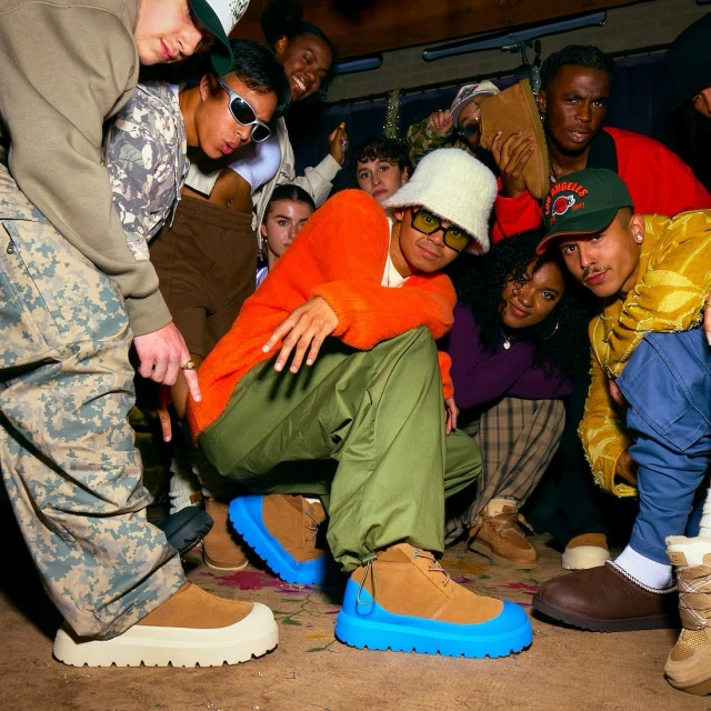Group of people wearing unique footwear in an indoor setting, showcasing diverse styles and colors, including blue-soled boots and camo pants.