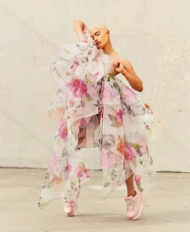 Model with bleached hair wearing a sheer floral organza dress and pink platform sneakers outdoors.