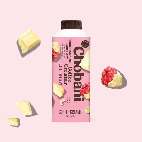Chobani white chocolate raspberry coffee creamer in a pink bottle, with white chocolate chunks and raspberries floating nearby.