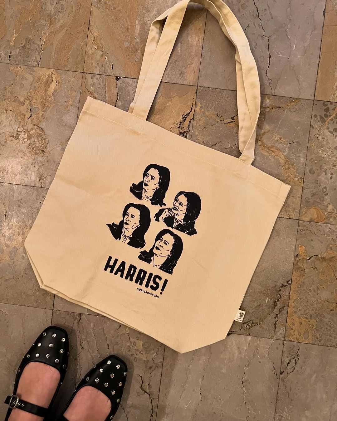 Tote bag with illustrations of Kamala Harris on a stone floor, paired with black buckled Mary Jane shoes, creating an urban, fashionable look.