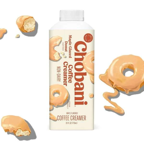 Chobani maple glazed donut coffee creamer in white carton with donut graphics, surrounded by donut pieces on a white background.