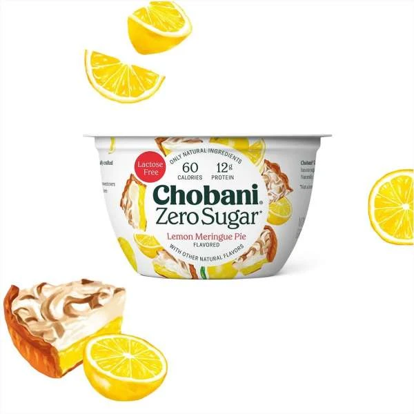 Chobani Zero Sugar Lemon Meringue Pie flavored yogurt in white container, surrounded by lemons and meringue pie slices on white.