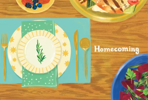 Overhead shot of a table setting with plates, cutlery, dishes of berries and vegetables, and the word 'Homecoming' on the wood surface.