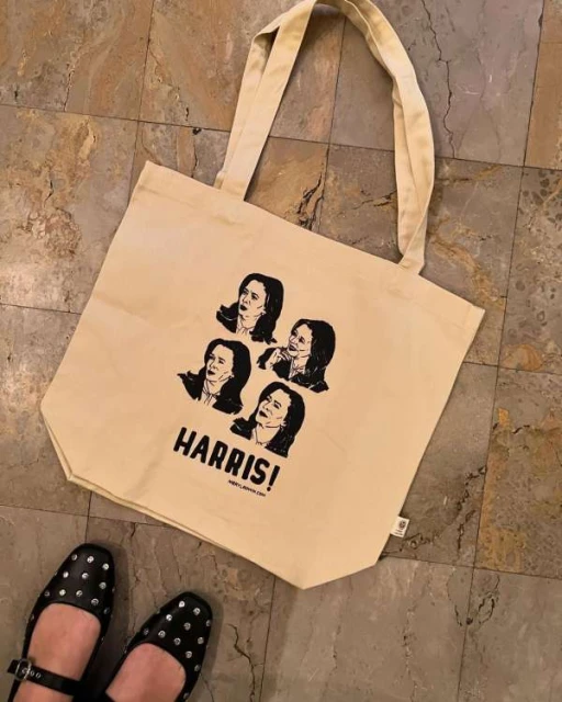 Tote bag featuring illustrations and text of Kamala Harris on tile flooring with the bottom of a person wearing studded flats.