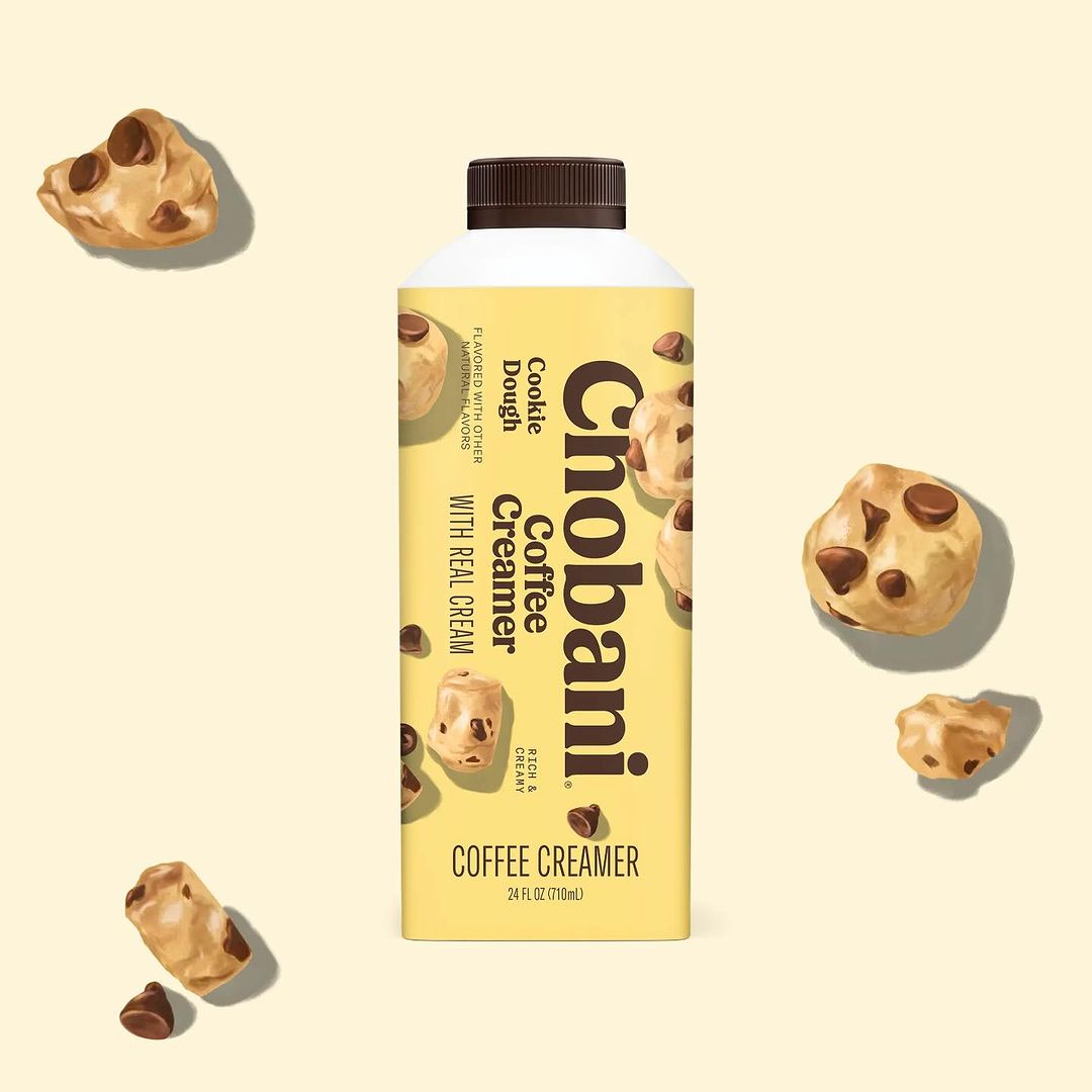 Chobani cookie dough flavored coffee creamer in a bottle, surrounded by cookie dough pieces on a light background, studio shot.