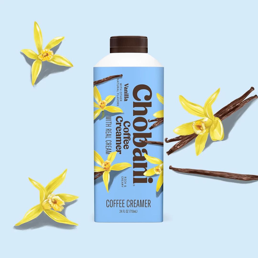 Chobani vanilla coffee creamer in carton surrounded by vanilla flowers and beans on a light blue background, product photography.
