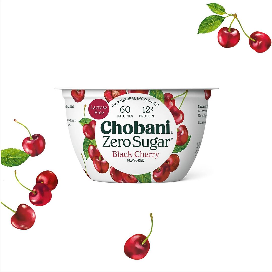 Chobani Zero Sugar Black Cherry yogurt in a white container with surrounding fresh cherries against a plain white backdrop.