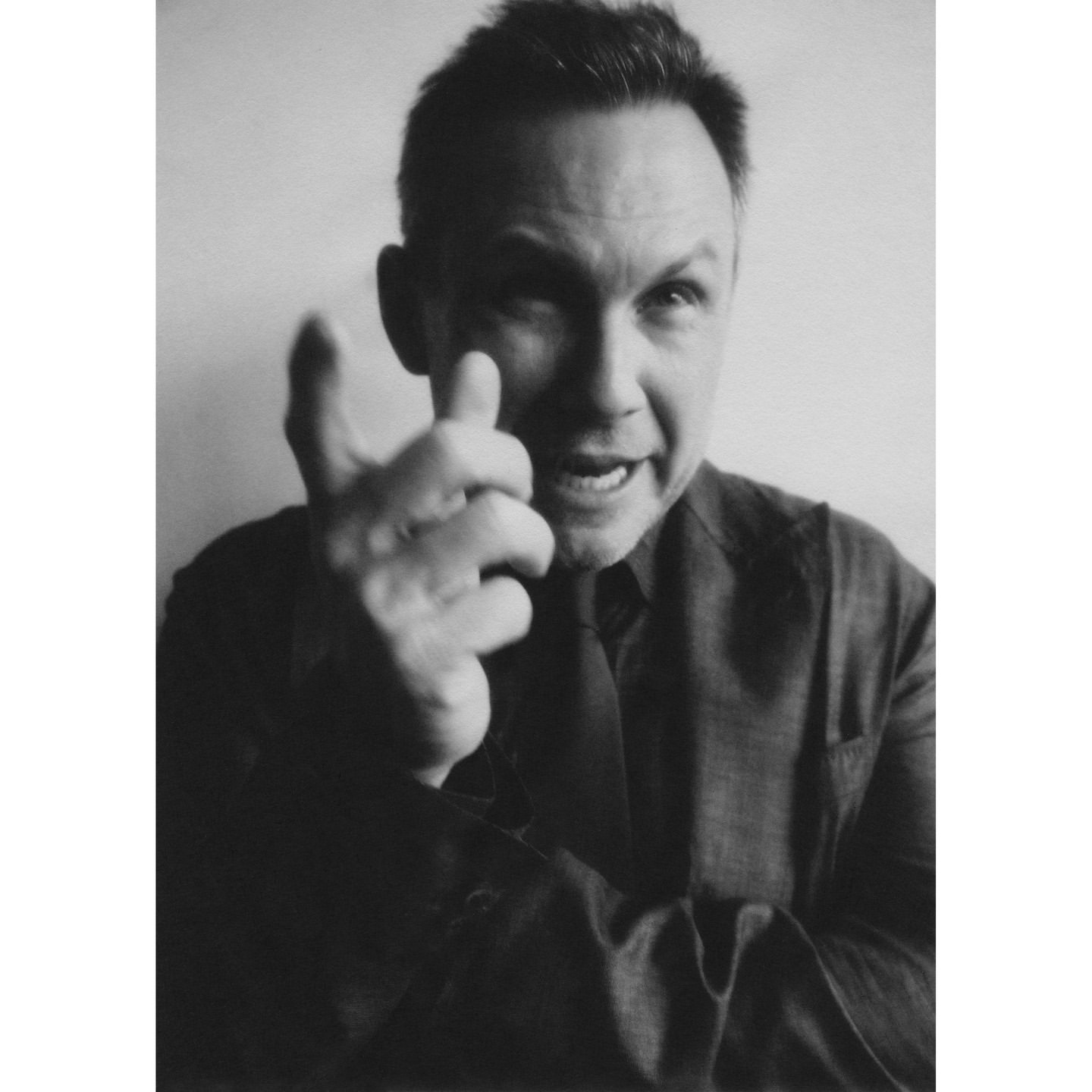 Monochrome portrait of a man in a blazer pointing a finger forward by Erik Tanner