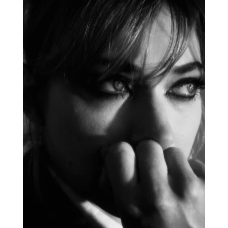 Close-up monochrome portrait of a woman with dark eye makeup and fingers near her face by photographer Erik Tanner.