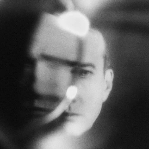 Monochrome portrait of an adult male with a soft focus, featuring diffused lighting and a dark background creating an abstract effect.