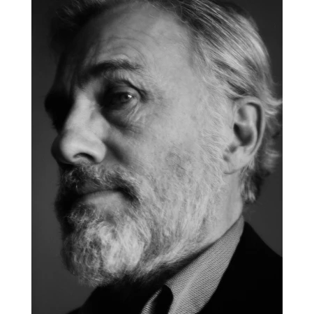 Close-up monochrome portrait of an older man with a full grey beard and mustache looking off to the side.