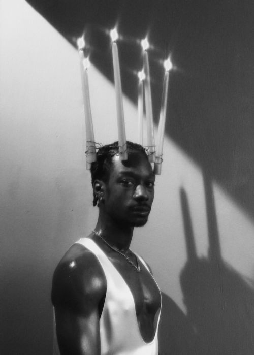 Portrait of a Black man wearing lit candles on his head by photographer Erik Tanner.