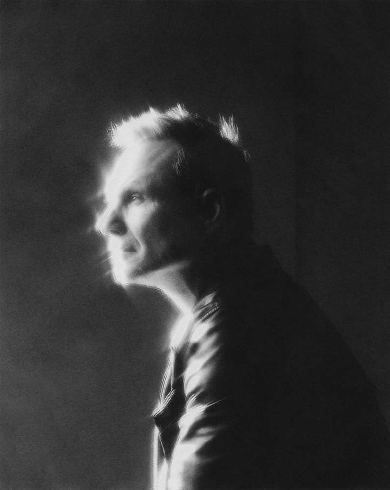 Black and white portrait of an adult male in profile, side lit, wearing a leather jacket against a dark background.