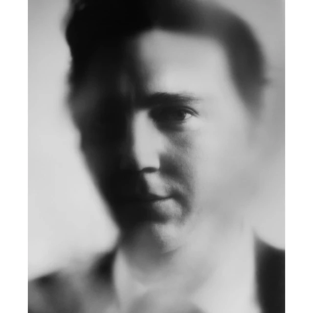 Monochrome portrait of an adult male with fair skin and dark hair, gazing directly at the camera with shallow depth of field.
