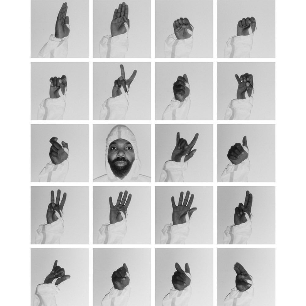 Black and white studio composite features a Black male in a white hooded jacket amidst a grid of hands signing in American Sign Language.