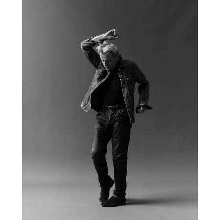 Man wearing denim jacket and jeans dancing in a studio portrait by Erik Tanner