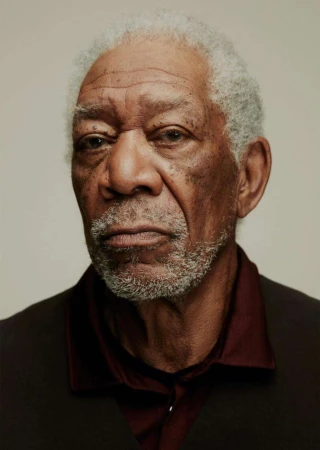 Portrait of an elderly adult African American man, indoors, wearing a dark-colored vest and maroon collared shirt, gray hair and beard.