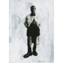 Full-length portrait of a Black man standing against a textured painted background, wearing a light jacket, dark shorts, and boots.