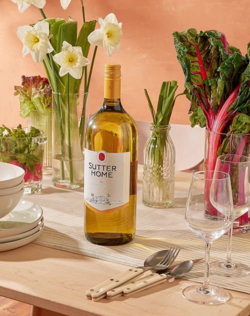 Sutter Home white wine bottle, silverware, glassware and flowers on a dining table, creating an inviting and refreshing ambiance.