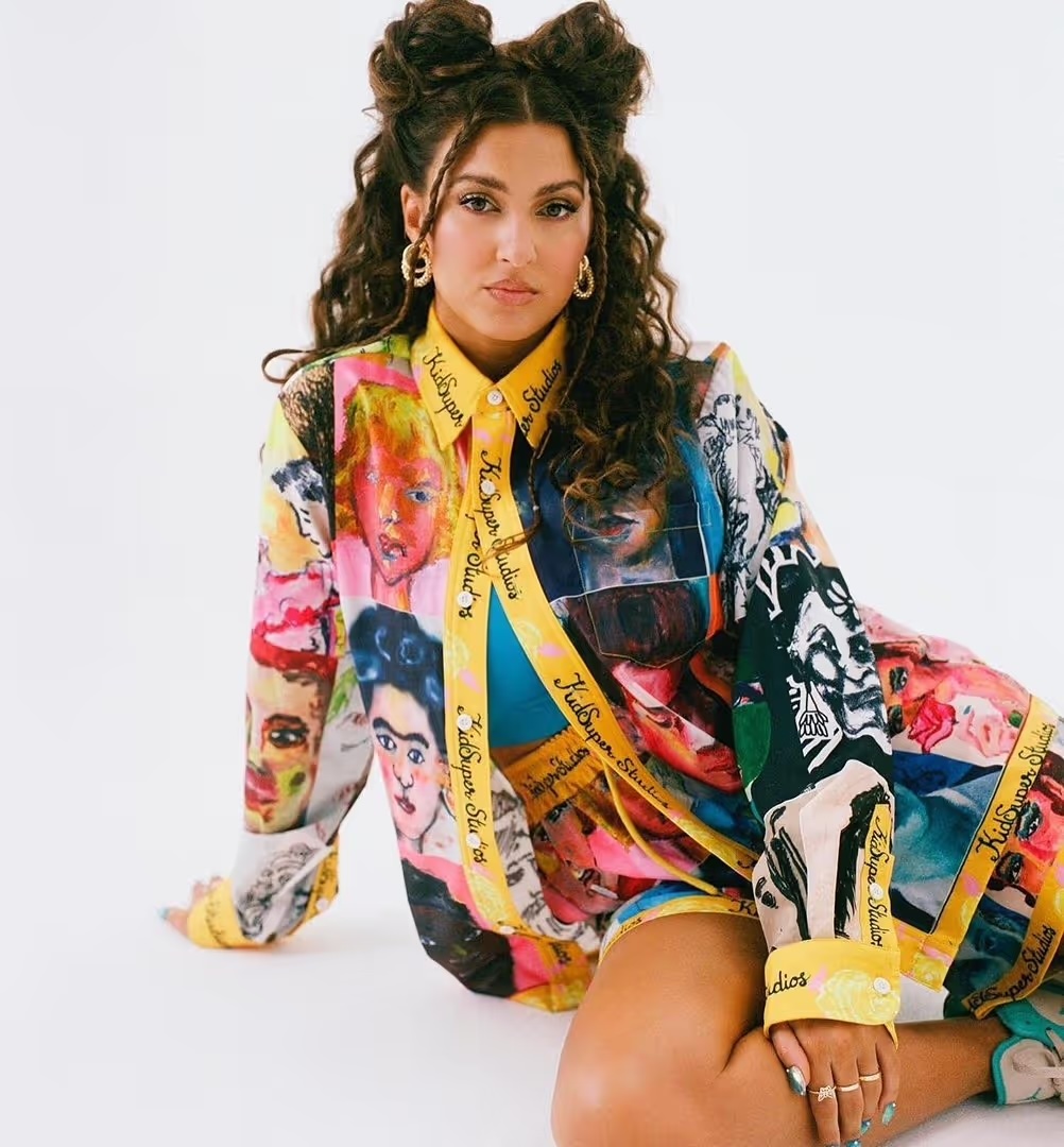 Brunette woman poses in colorful printed shirt and shorts, indoor photo studio setting, white backdrop. Fashion photography, portrait view.