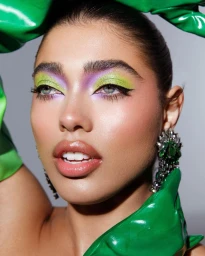 Close-up portrait of a woman wearing vibrant green and purple eyeshadow, green gloves, and jeweled earrings