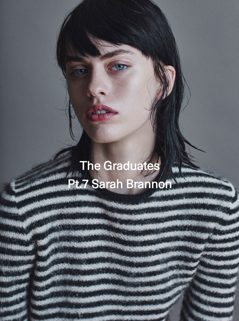 Close-up portrait of a young adult female model with dark hair and a striped sweater against a neutral grey background in a photo studio.