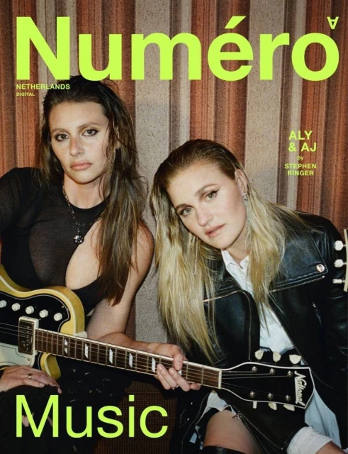 Magazine cover features two musicians, Aly & AJ, with guitars. Neon 'Numéro' logo tops the image, against striped backdrop.