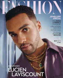 Portrait of Lucien Laviscount wearing layered gold chains and a purple shirt for a magazine cover with makeup by Amber Amos