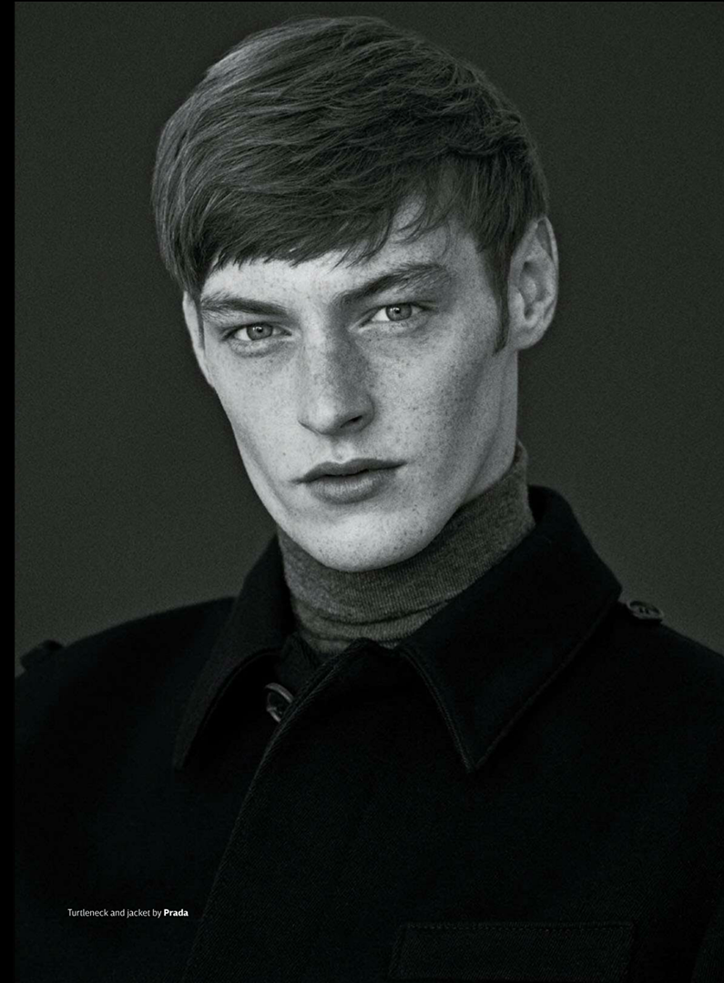 Monochromatic portrait of a young adult male with light skin and brown hair. He's wearing a dark jacket and turtleneck.