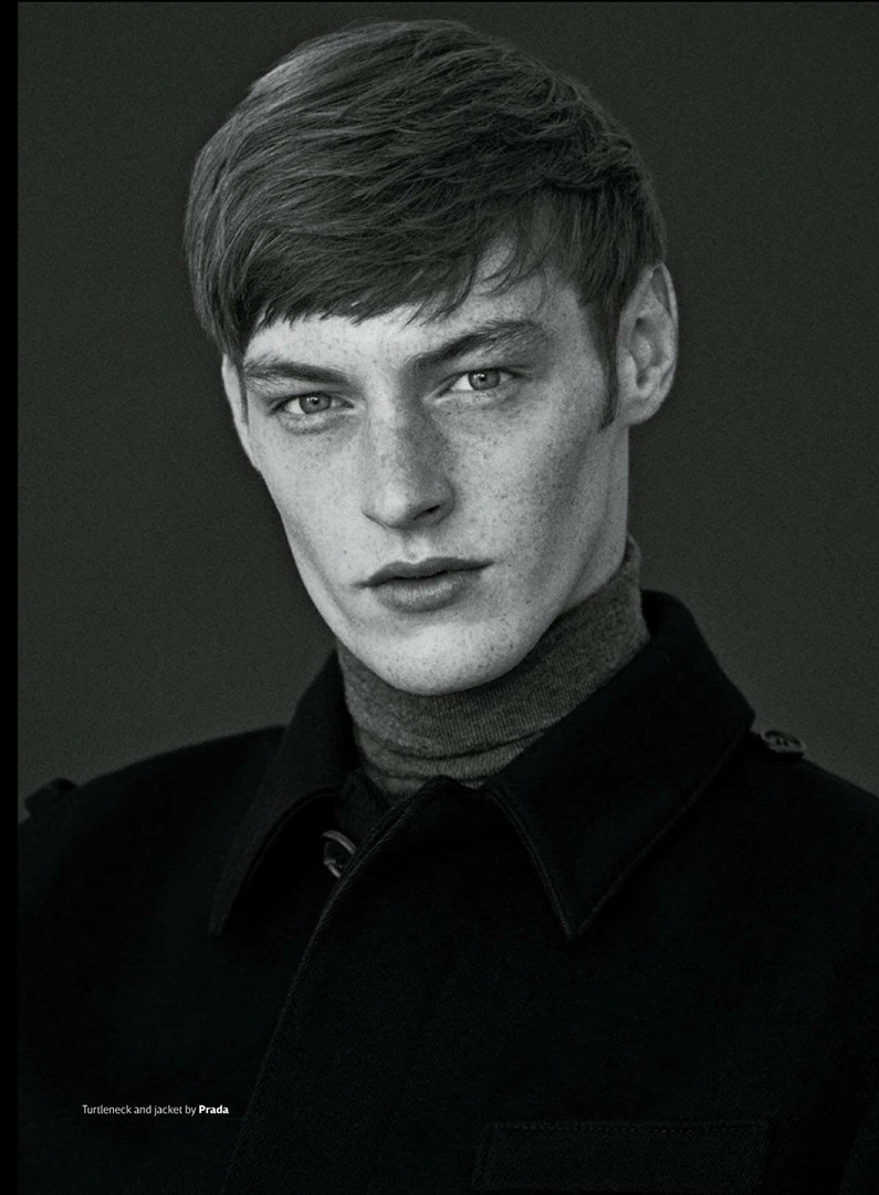 Close-up monochrome portrait of a young man with short dark hair wearing a turtleneck and dark jacket