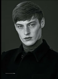 Close-up monochrome portrait of a young man with short dark hair wearing a turtleneck and dark jacket