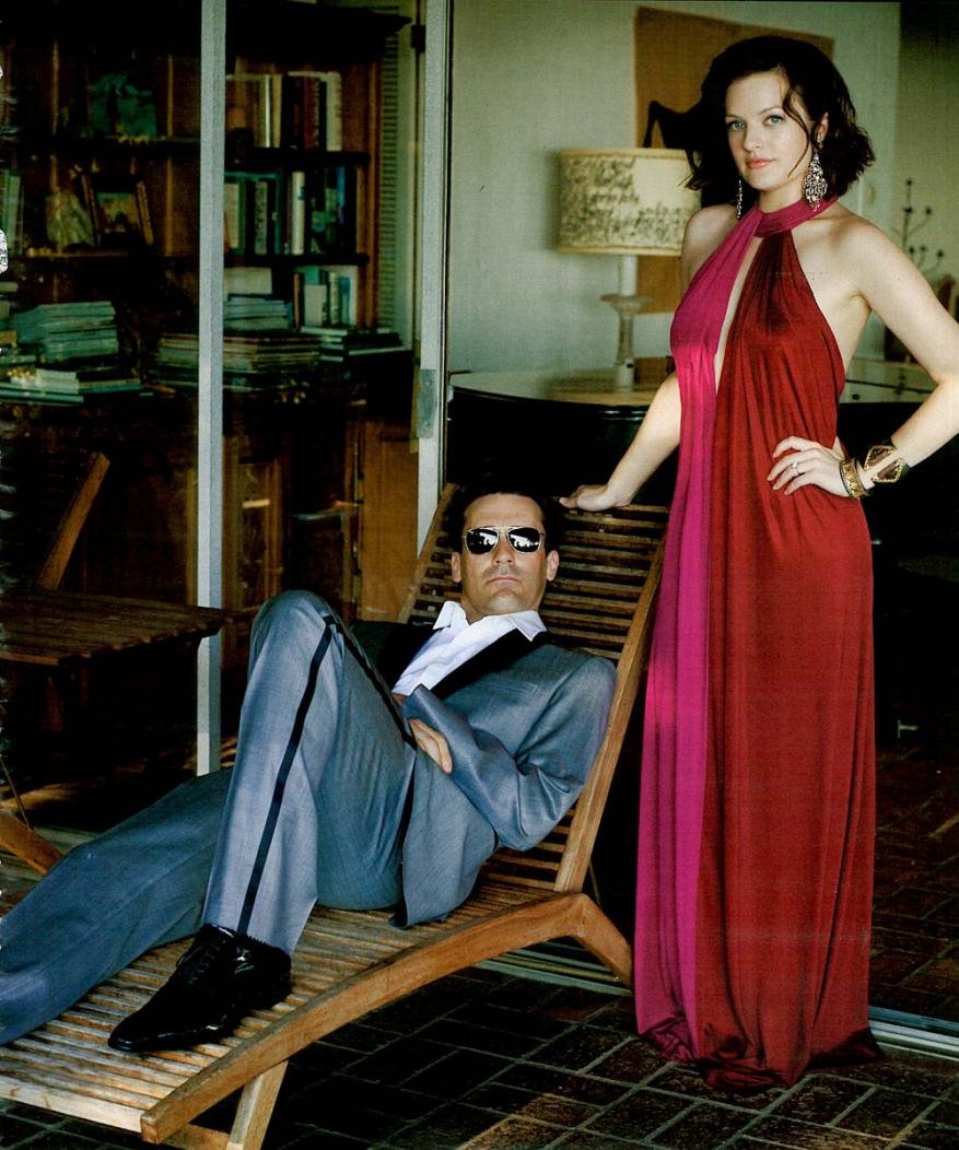 Elegant photo of a man in a suit reclining on a wooden lounger and a woman in a gown, set against a backdrop of bookshelves and neutral tones.