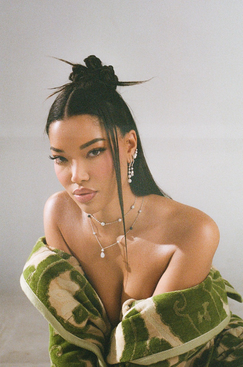 Striking portrait of an Asian woman with elegant hair, jewelry, and a green patterned towel. Beauty shot with a clean backdrop.