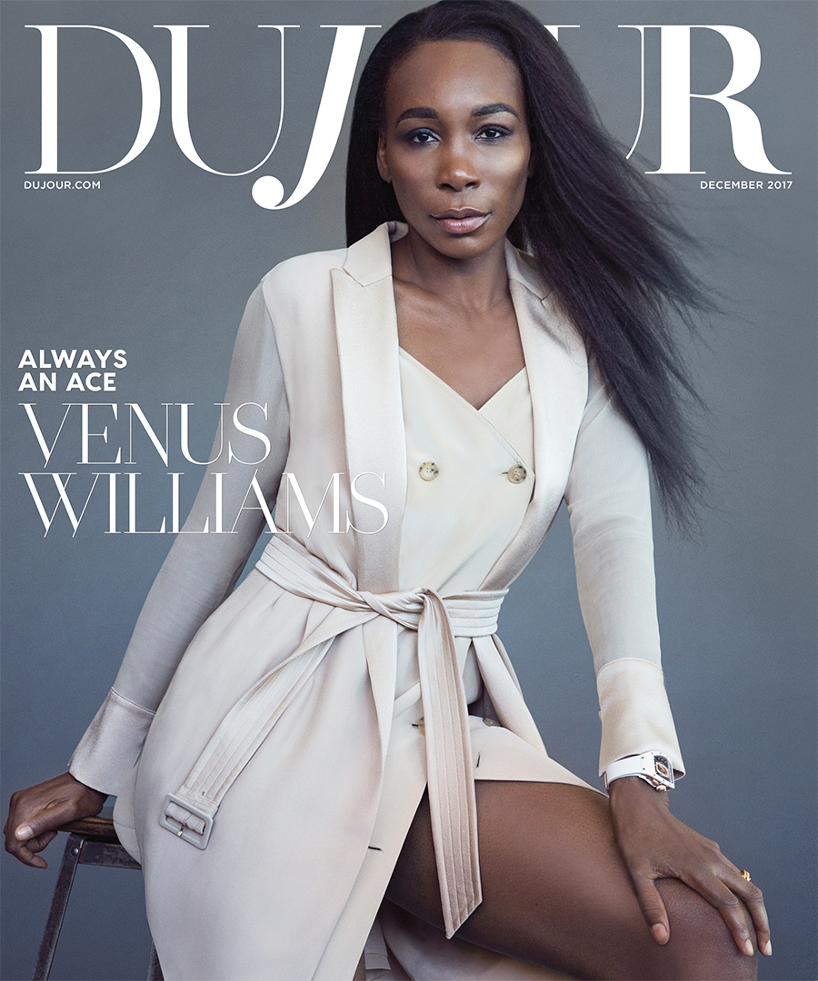 Venus Williams on the cover of DuJour Magazine December 2017 wearing a beige trench coat dress and sitting on a grey stool.