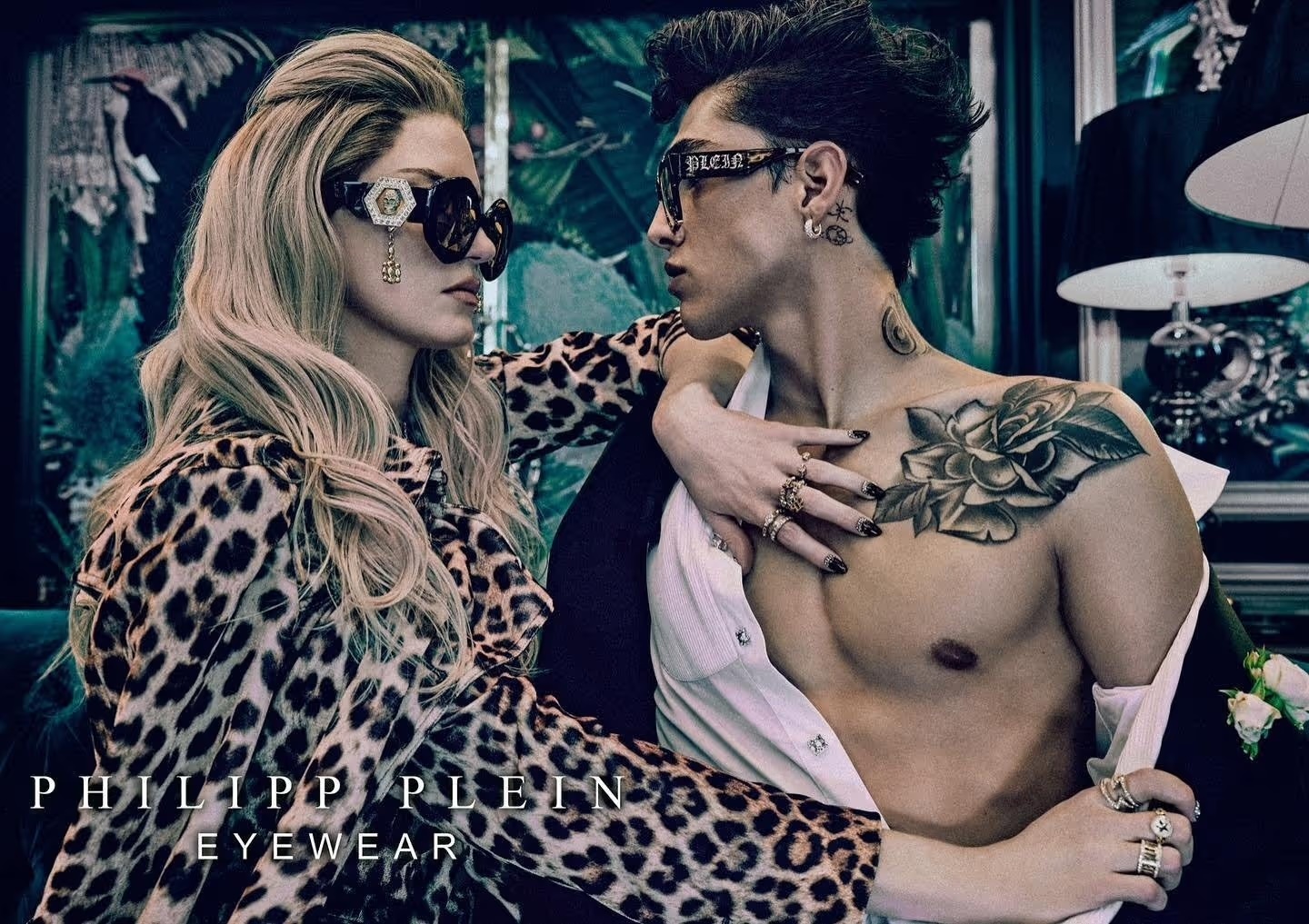 Fashion shot featuring a woman in a leopard print coat and sunglasses alongside a man with tattoos and sunglasses, advertising eyewear.