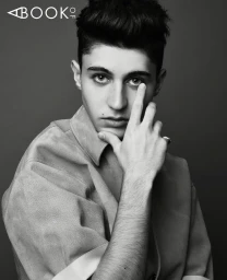 Portrait of young man with styled dark hair touching his face wearing collared shirt