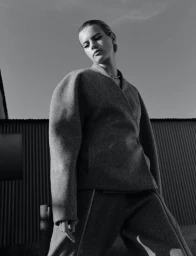 Low angle monochrome fashion portrait of a woman wearing a structured wool jacket and trousers.