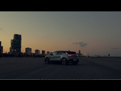 Silver SUV parked in an urban landscape at twilight. The car is the primary subject, with city buildings in the background.