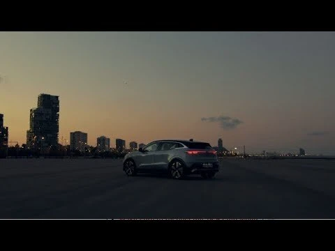 Silver SUV parked in an urban landscape at twilight. The car is the primary subject, with city buildings in the background.