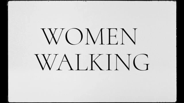 Black and white image with the words WOMEN WALKING in a sans-serif font centered on a plain white background.
