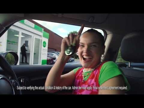 Smiling woman in car interior holding car keys up in the air, showcasing happiness and vehicle ownership in a bright setting.