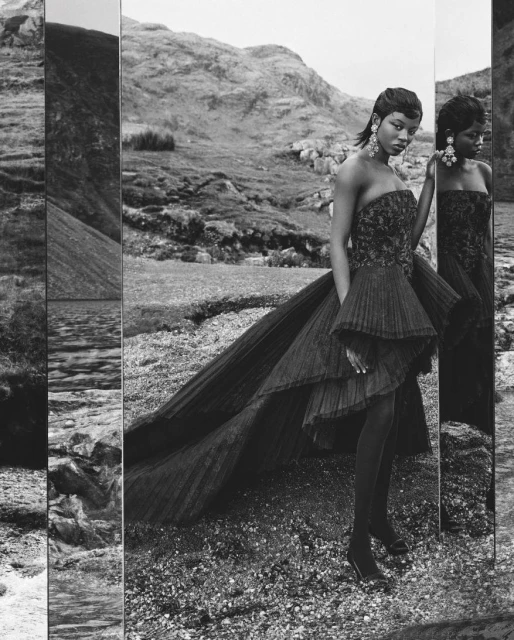 Fashion shot of a Black woman in a black couture gown with a mountain background, reflected in a tall mirror in a black and white photograph.