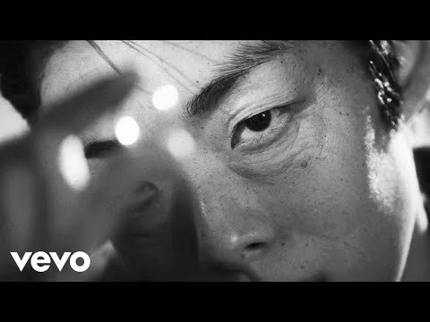 Close-up black and white portrait of an East Asian man with bokeh light flares across his face by Celia Arias