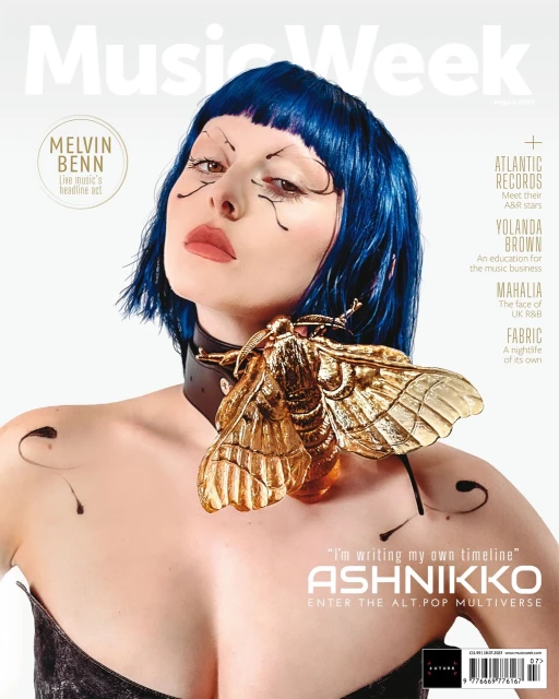 Music Week magazine cover featuring Ashnikko with blue hair and unique makeup, adorned with a large golden moth accessory, against a white backdrop.