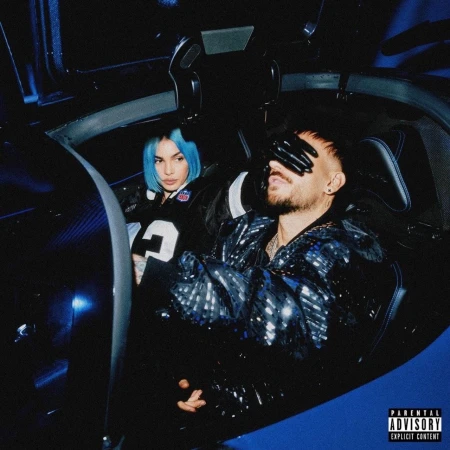 Moody indoor shot of a man with gloved hands over eyes and a woman with blue hair inside a car, bathed in blue light.